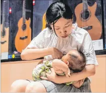  ??  ?? Shanghái. Wang Chao alimenta a su hijo en su tienda de guitarras.