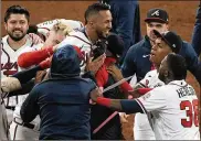  ?? AP ?? Atlanta Braves’ Eddie Rosario is congratula­ted by teammates after hitting the game winning RBI single during the ninth inning against the Los Angeles Dodgers in Game 2 Sunday. The Braves defeated the Dodgers 5-4.