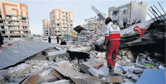  ?? Pouria Pakizeh ?? > A rescue worker searches debris for survivors with his sniffing dog after an earthquake at the city of Sarpol-e-Zahab in western Iran