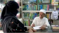  ?? — AFP ?? A file photo shows novelist Kasem bin Abubakar signing an autograph for a relative at his book shop in Dhaka.