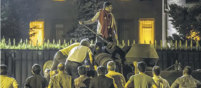  ??  ?? Citizens opposing the coup stop a tank driven by coup plotters outside the Office of the Chief of General Staff in Ankara on July 15, 2016.