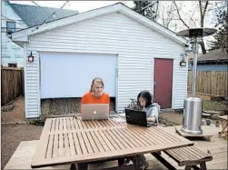  ??  ?? Amy Nedoss and her 9-year-old daughter Jin work on their laptops in their newly remodeled backyard space Nov. 5 in Evanston. She hired Nick Lawson as her contractor for this project, who has seen a bump in business because of the pandemic, both for his work as a contractor and landscaper.