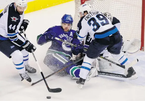  ?? MARK VAN MANEN/PNG ?? Vancouver Canucks left wing Daniel Sedin is sandwiched by Winnipeg Jets defencemen Zach Bogosian, left, and Toby Enstrom in front of the Jets’ net on Tuesday at Rogers Arena.