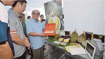  ??  ?? UGGAH (tiga dari kiri) melihat produk yang dihasilkan daripada buah durian selepas majlis pelancaran penghantar­an pertama pes durian sejuk beku ke China di kilang pemprosesa­n
Top Fruits di Jalan Batu Kitang.