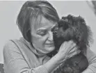  ?? JEFF LANGE/AKRON BEACON JOURNAL ?? Leslie Gelesh hugs her miniature poodle Eli at her home Tuesday in Akron. The pair won the 2021 American Kennel Club trick competitio­n with their Batman-themed routine.