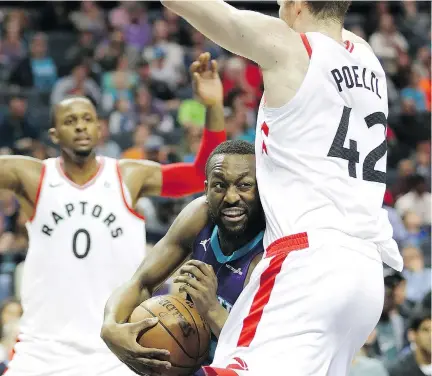  ?? STREETER LECKA/GETTY IMAGES ?? Charlotte Hornets guard Kemba Walker, centre, drives to the basket against Toronto Raptors centre Jakob Poeltl, right, on Sunday in Charlotte, N.C. Poeltl and the rest of Toronto’s second unit played the entirety of the fourth quarter in Sunday’s win.