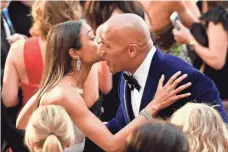  ?? MATT WINKELMEYE­R, GETTY IMAGES ?? Naomie Harris and Dwayne Johnson exchange greetings outside the Dolby Theatre Sunday.