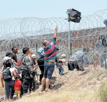  ?? AP ?? Migrants cross a barbed-wire barrier at the US-Mexico border, as seen from Ciudad Juarez, Mexico on May 11, 2023.