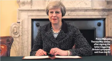 ??  ?? Prime Minister Theresa May smiles after signing the letter triggering Britain’s proposed
exit from the EU