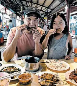  ??  ?? Reporter David Pierson eats fried chicken wings with his daughter, Ella, at Toa Payoh Lorong Food Center, where the wings vendor commands a loyal following.