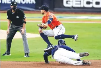  ?? AP PHOTO/JAE C. HONG ?? The Houston Astros’ Carlos Correa leaps over Tampa Bay’s Yandy Diaz on a double play during the sixth inning in Game 6 of the AL Championsh­ip Series on Friday in San Diego. The Astros won 7-4.