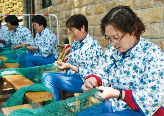  ??  ?? Women weave fishing net with straw ropes to catch jellyfish. — He Jiangyong