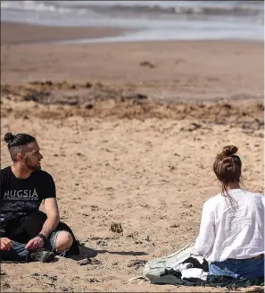  ??  ?? FEELING THE HEAT: An officer advises a couple at Portobello beach last Wednesday about the rules to stay at home unless getting exercise or food