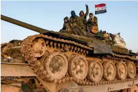  ?? AFP ?? A Syrian soldier gestures as he sits with comrades atop a tank being transporte­d near the northern town of Manbij. —