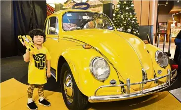  ??  ?? A child taking a photo together with the Volkswagen Beetle and Bumblebee Toy for #BeeatAtria photo contest.