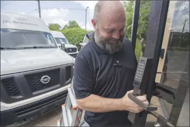  ?? (NWA Democrat-Gazette/J.T. Wampler) ?? Joshua Jones, owner of Sharp’s Lock & Alarm, installs a standalone storefront access control system Friday at a Fayettevil­le business. Fayettevil­le is considerin­g changes to its ordinance dealing with false security alarms, including reducing the fees property and business owners can get for having too many in a year. Visit nwaonline.com/photo for today’s photo gallery.