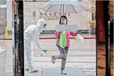  ?? — AFP photo ?? A hotel employee wearing a protective suit sprays disinfecta­nt on an arriving guest in Wuhan, a day after travel restrictio­ns into the city were eased following the outbreak.
