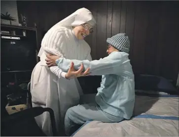  ?? Barbara Davidson Los Angeles Times ?? SISTER MARIA Socorro helps Esperanza Calderon into bed in her East L.A. home. When Socorro was 18, she went to a retreat in an effort to dissuade her sister from becoming a nun, but found “God was calling me.”