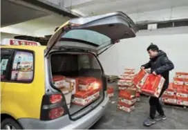  ??  ?? Qiangsheng taxi driver Chen helps the family deliver 60 boxes of apples and pears to customers in the Pudong New Area.