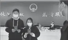  ?? WANG JING / CHINA DAILY ?? Xie Linhui (left) and Shang Qin get their marriage certificat­es at the marriage registrati­on office in Qiaokou district in Wuhan, Hubei province, on Tuesday.