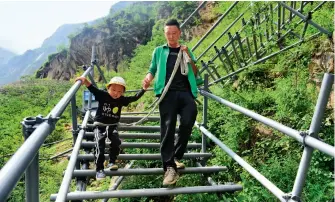  ??  ?? 悬崖村村民沿着新建的­钢梯下山 图 / 董宁