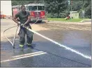  ??  ?? A Darby firefighte­r hoses mud away at the Darby Town Center.