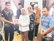  ?? ?? Nancy hands over RM3,000 cash assistance to Joanna’s husband Haslie Ali during her visit to Kampung Engkaroh in Serian.