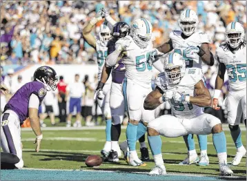  ?? ASSOCIATED PRESS / FILE ?? Dolphins defensive end Cameron Wake (91) celebrates after sacking Baltimore quarterbac­k Joe Flacco (left) during the 2014 season. Miami will play the Ravens on the road in Week 8, and it could be a tough battle.