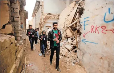  ?? Reuters ?? MEMBERS of a civil activist group distribute flowers on Valentine’s Day in war-battered Mosul, Iraq, yesterday. Security in the country has dramatical­ly improved after Iraqi security forces fully defeated the extremist Islamic State militants in 2017. However, small groups and individual­s of extremist militants regrouped in urban and rugged areas, and still carry out attacks against the security forces and civilians.