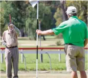  ??  ?? Left: Rolf Lobert lines up his putt as Gilbert Davis holds the flag during the senior competitio­n at Drouin Golf Club on Thursday. Photograph­s: Michael Robinson.