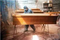  ??  ?? A worker paints coffins made of Mapresa (pressed wood) before painting them at a factory at Juan de Lurigancho district in Lima.