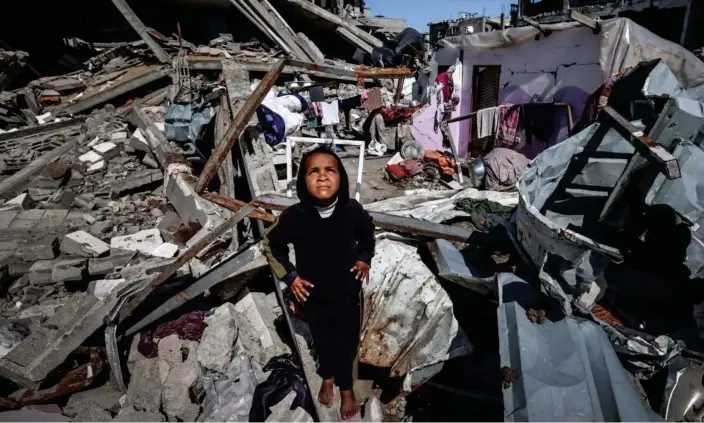  ?? Photograph: Mohammed Abed/AFP/Getty Images ?? A Palestinia­n girl looks at a military drone as she stands on the rubble of destroyed houses in the Rafah refugee camp on Thursday.
