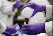  ?? ?? Eva Stebel, water researcher, pours a water sample into a smaller glass container for experiment­ation at the U.S. Environmen­tal Protection Agency Center For Environmen­tal Solutions and Emergency Response in Cincinnati on Feb. 16.