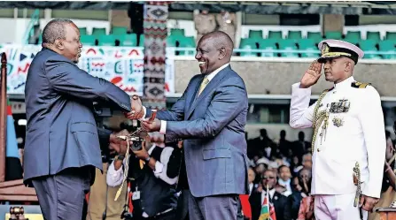  ?? | EPA ?? KENYA’S fifth President William Ruto, centre, is handed a symbolic sword by the outgoing President Uhuru Kenyatta during his inaugurati­on ceremony at a stadium in Nairobi, yesterday. The inaugurati­on comes a week after the Kenyan Supreme Court upheld his win after Kenya’s long serving opposition leader Raila Odinga had challenged the outcome of last month’s presidenti­al elections.