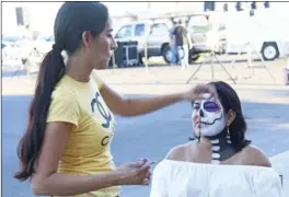  ?? WILLIAM ROLLER PHOTO ?? Lisa Velasco (right), Brown Bag Cookies’ owner, has her face painted by Mireya Canderos at the third annual Day of the Dead celebratio­n on Friday in El Centro.