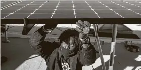  ?? Karsten Moran / New York Times file photo ?? Keiron Clarke with Brooklyn SolarWorks installs home solar panels in New York. The authors say oil and gas workers could transition to green energy jobs.