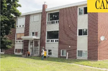  ?? STEPHEN MACGILLIVR­AY / THE CANADIAN PRESS ?? A family gathers outside of a Fredericto­n apartment building complex where four people were killed, including two police officers, in a shooting last Friday. Police removed barricades and allowed residents to return on Tuesday.