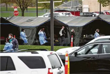  ?? Associated Press file photo ?? Health care workers run a coronaviru­s testing site in May at a parking lot in Sioux Falls, S.D. That state and North Dakota have the nation’s worst rates of coronaviru­s deaths per capita in the last 30 days.