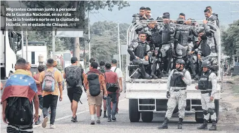  ?? /EFE ?? Migrantes caminan junto a personal de la Guardia Nacional, en su ruta hacia la frontera norte en la ciudad de Huixtla, en el estado de Chiapas.