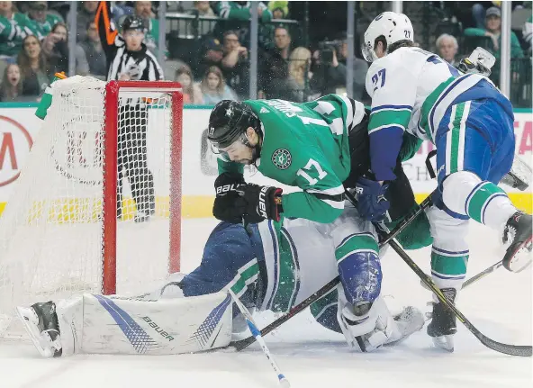  ?? — AP FILES ?? Dallas Stars centre Devin Shore crashes into Canucks goalie Jacob Markstrom Sunday as defenceman Ben Hutton joins the fray during Sunday’s 6-0 shellackin­g of the Stars in which Markstrom posted a shutout after calling himself and his teammate out on...