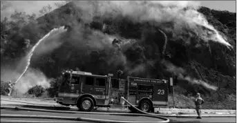  ?? AP PHOTO/CHRISTIAN MONTERROSA ?? firefighte­rs begin hosing down the flames of a wildfire called the palisades fire minutes after it ignites on Monday in pacific palisades, a suburb of los Angeles.