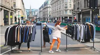  ?? AFP ?? Retail workers move rails of clothes between stores on London’s Oxford Street yesterday as non-essential retailers, closed during the lockdown, prepare to reopen on Monday.