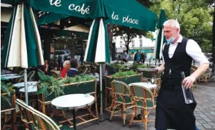  ?? AP PHOTO/FRANCOIS MORI ?? A waiter walks to serve customers at a restaurant Monday in Paris.
