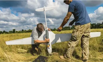  ?? DAVID GUTTENFELD­ER/THE NEW YORK TIMES ?? Ukrainian troops practice attaching a dummy bomb to the undercarri­age of a Punisher, a high-end fixed-wing military drone manufactur­ed in Ukraine, on July 25 in an open field on the outskirts of Kyiv.