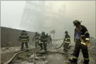  ?? MARK LENNIHAN — THE ASSOCIATED PRESS FILE ?? Frefighter­s work beneath the destroyed mullions, the vertical struts which once faced the outer walls of the World Trade Center towers, after a terrorist attack on the twin towers in New York. New research released on Friday suggests firefighte­rs who arrived early or spent more time at the World Trade Center site after the 9⁄11 attacks seem to have a greater risk of developing heart problems than those who came later and stayed less.