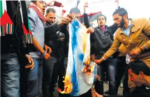  ?? (Muhammad Hamed/Reuters) ?? JORDANIANS BURN an Israeli flag in front of the parliament in Amman on Tuesday.