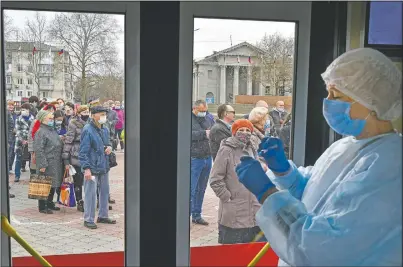  ?? (AP/Alexander Polegenko) ?? A Russian medical worker prepares a shot of Russia’s Sputnik V coronaviru­s vaccine as people line up to at a mobile vaccinatio­n center in Simferopol, Crimea.