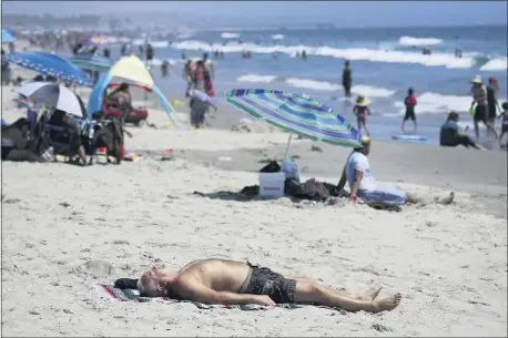  ?? MARCIO JOSE SANCHEZ — THE ASSOCIATED PRESS FILE ?? In this Sunday, July 12, 2020, file photo, a man lies on the beach amid the coronaviru­s pandemic in Santa Monica California faces a heat wave Friday, Aug. 14, 2020, that could bring dangerousl­y high temperatur­es throughout the state, along with the threat of wildfires and spreading coronaviru­s infections as people flock to beaches and recreation areas.