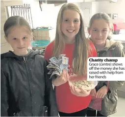  ??  ?? Charity champ Grace (centre) shows off the money she has raised with help from her friends