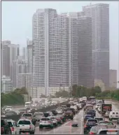  ?? (AP/Wilfredo Lee) ?? Drivers navigate rainy rush-hour traffic Thursday in front of the skyline of Miami.